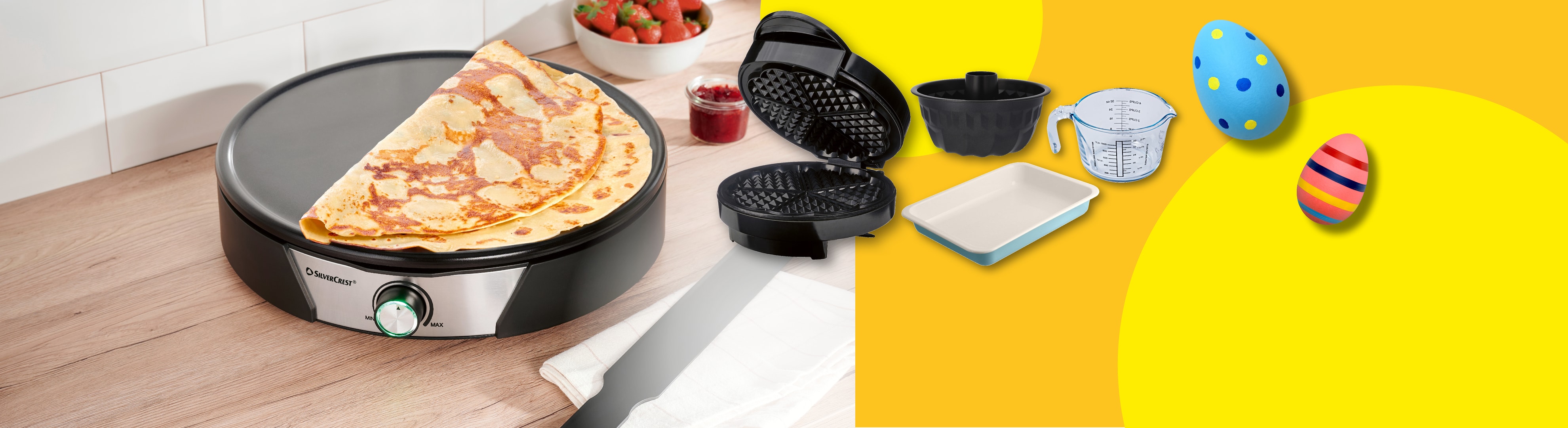 Crêpes-Maker mit Crêpes, Waffeleisen, Backformen und Ostereiern auf gelbem Hintergrund.
