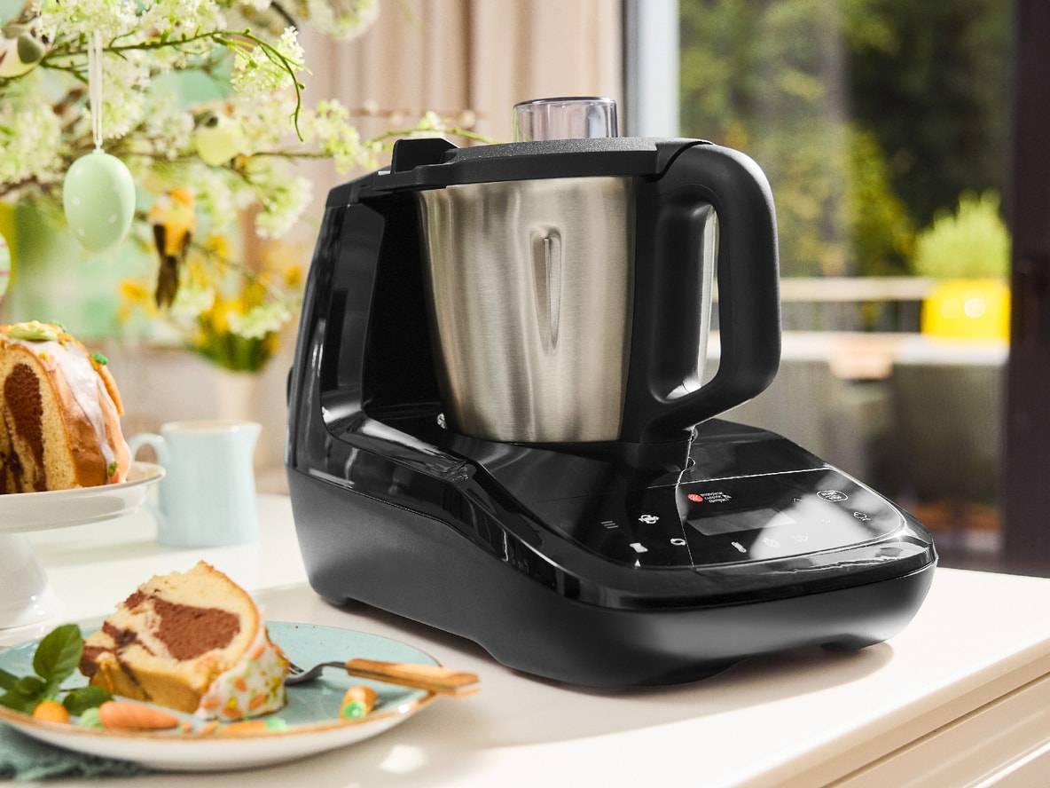 Monsieur Cuisine Smart Küchenmaschine auf einer Arbeitsplatte mit Osterkuchen und Dekorationen.