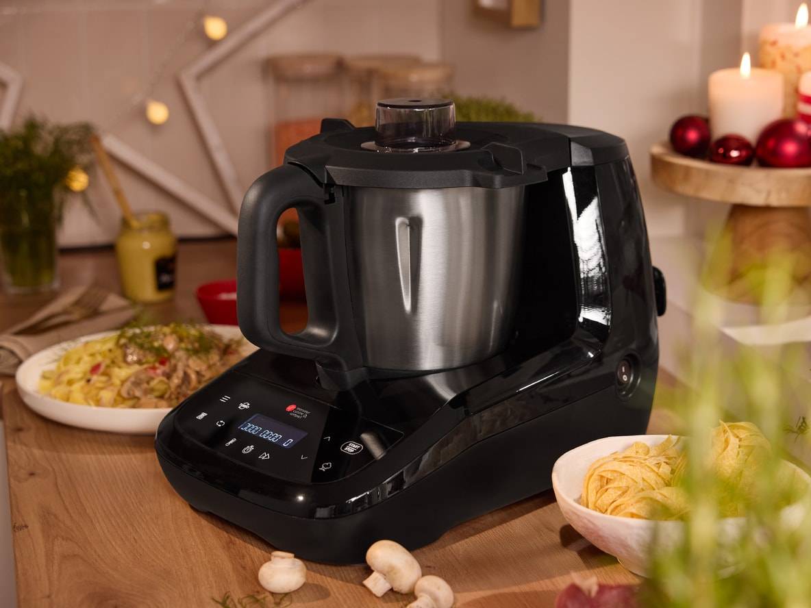 Monsieur Cuisine Smart Küchenmaschine auf einer Holztheke mit Nudelgerichten und Weihnachtsdekoration.