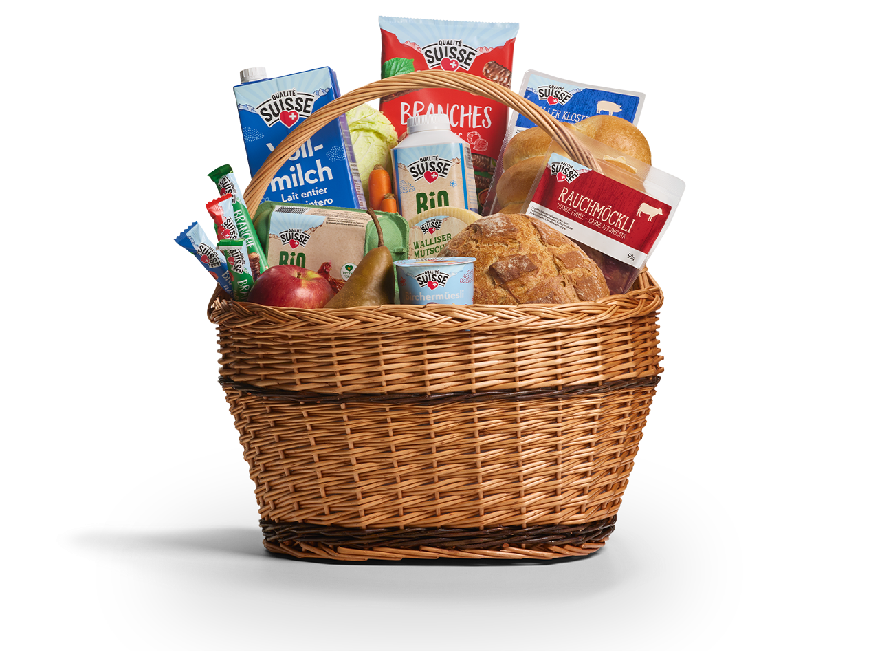 Weidenkorb gefüllt mit Schweizer Lebensmitteln, darunter Milch, Brot, geräuchertes Fleisch und Obst.
