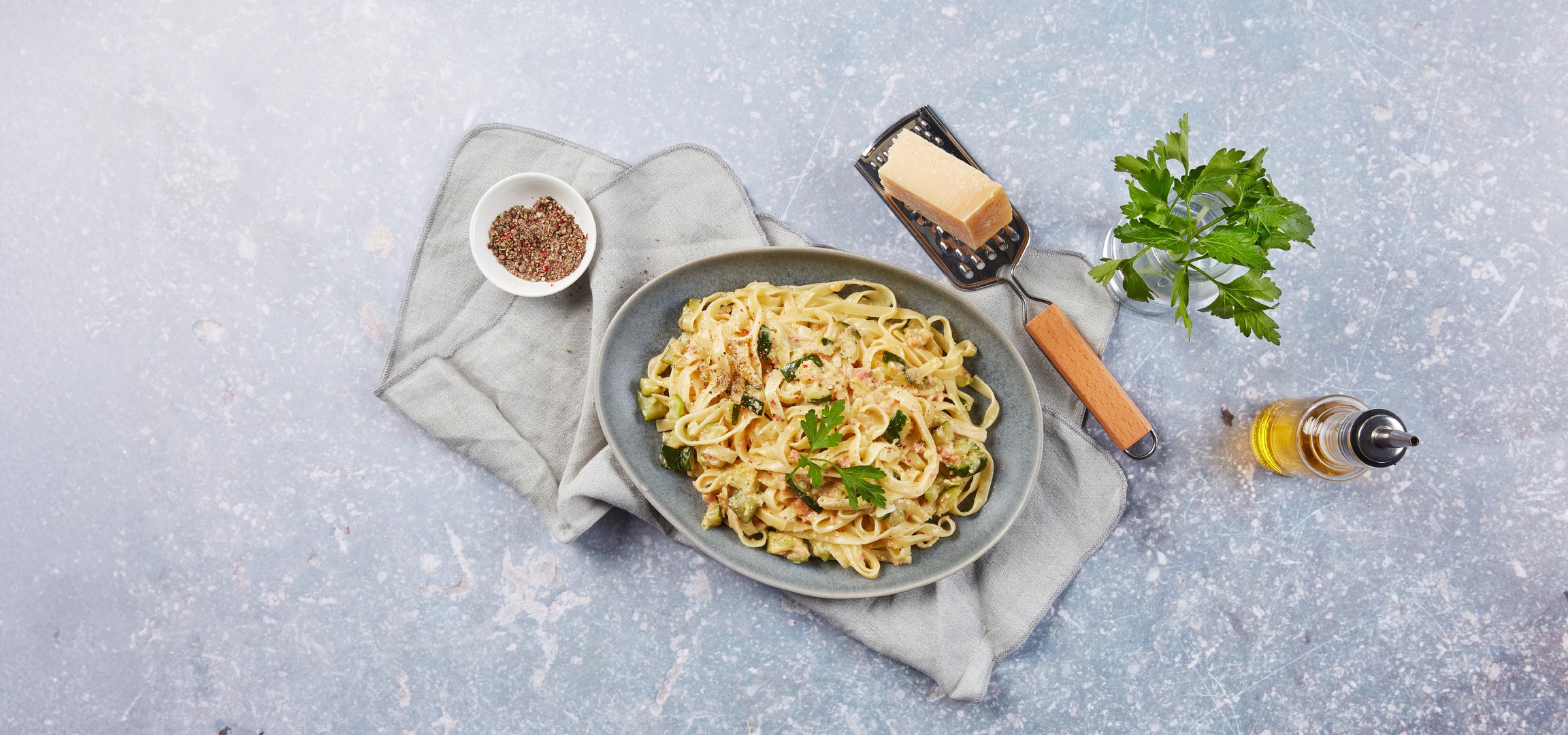 Cremige Pasta mit Zucchini und Speck, dazu Parmesan und Gewürze.