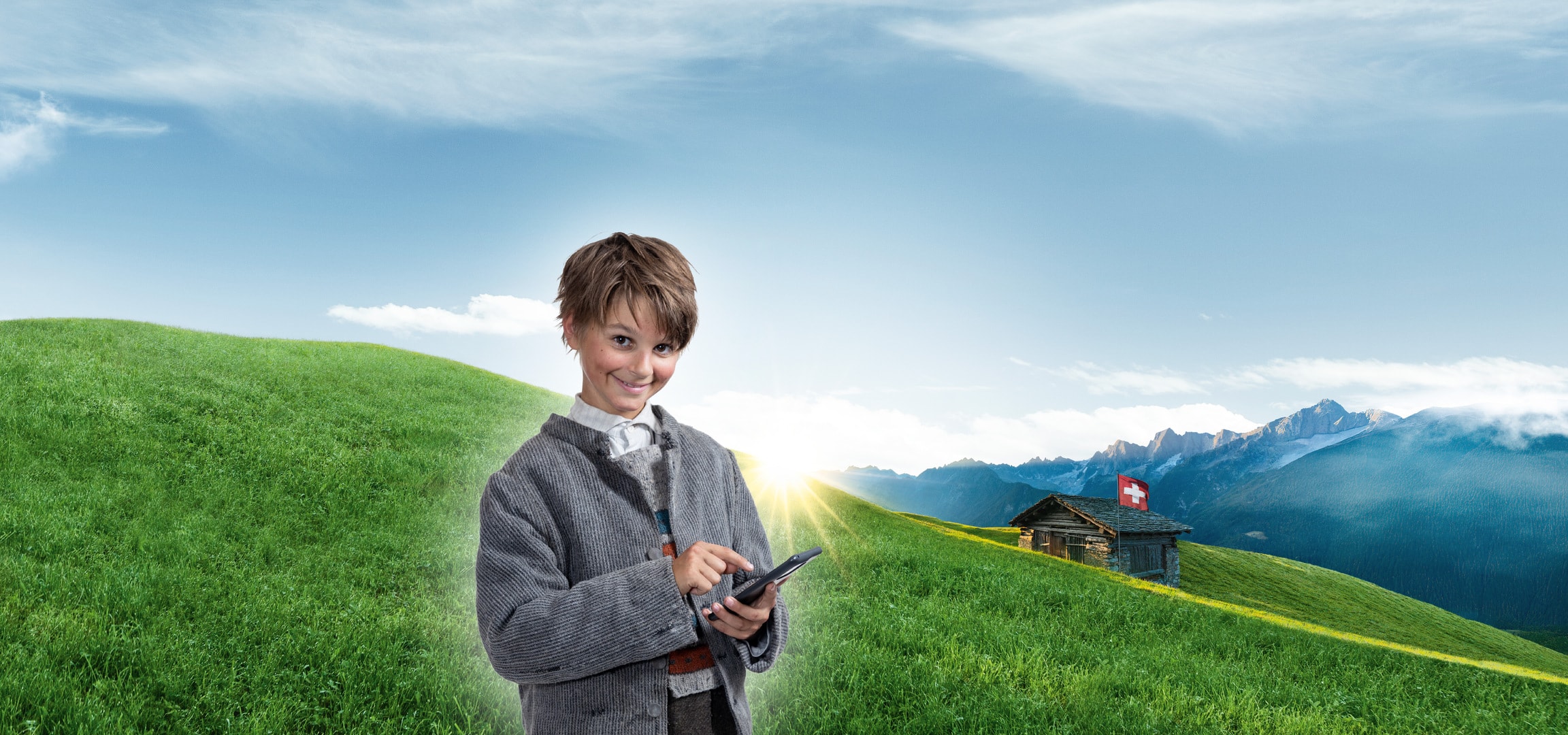 Lächelndes Kind in Schweizer Tracht mit Tablet in alpiner Landschaft.