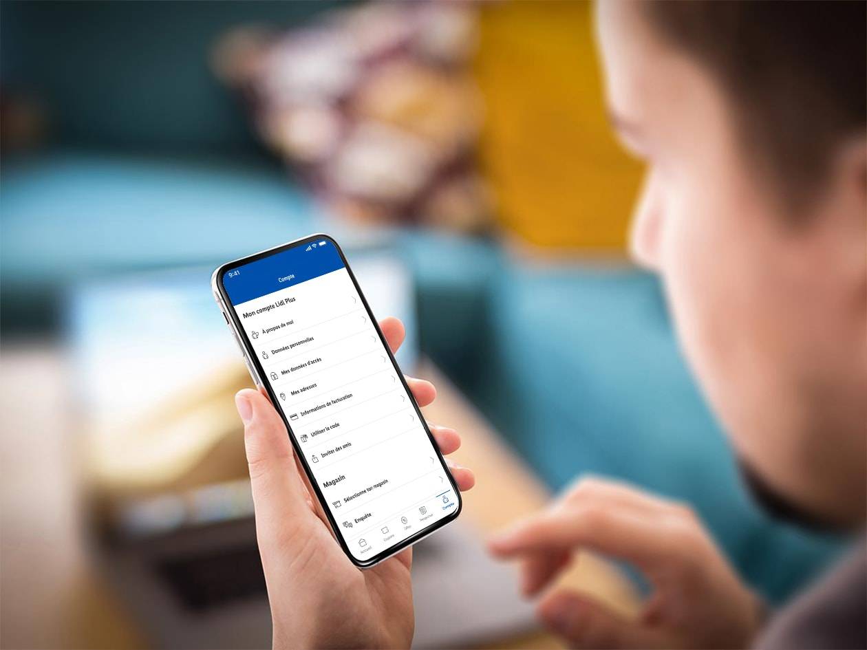 Une personne utilise l'application Lidl Plus sur son smartphone, affichant les options de compte.