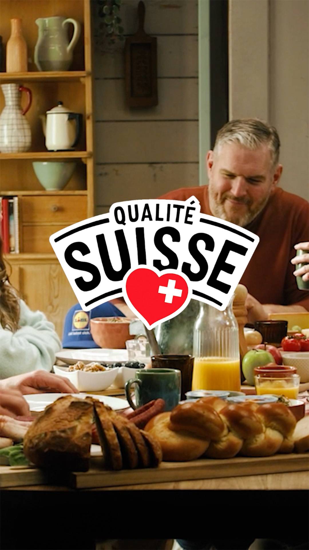 Petit-déjeuner familial avec pain, jus d'orange et fruits, avec le logo 'Qualité Suisse'.
