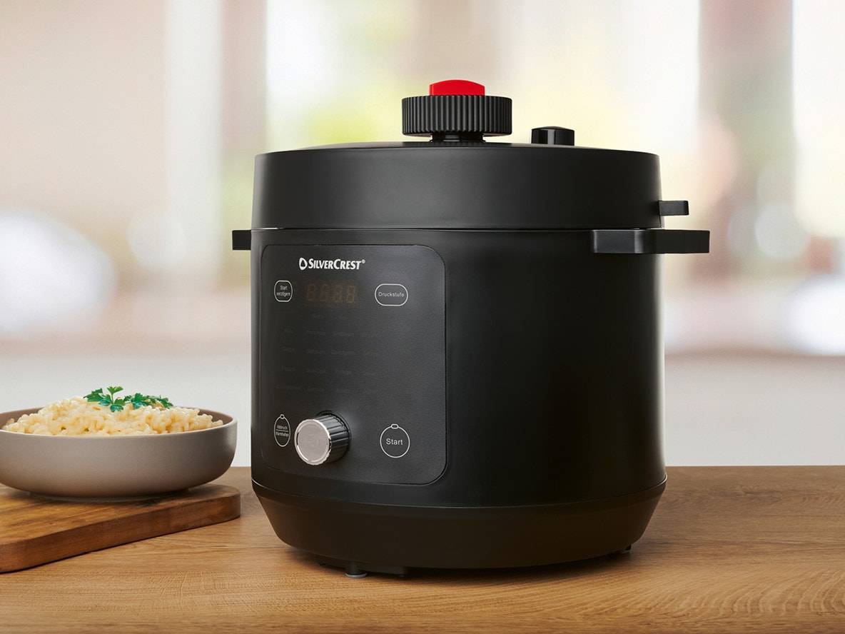 Autocuiseur électrique noir sur une table en bois avec un bol de riz.