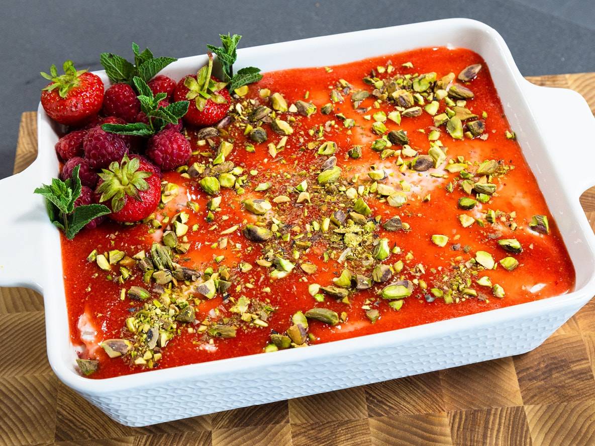 Dessert avec garniture de fraises et framboises, décoré de pistaches et de menthe.