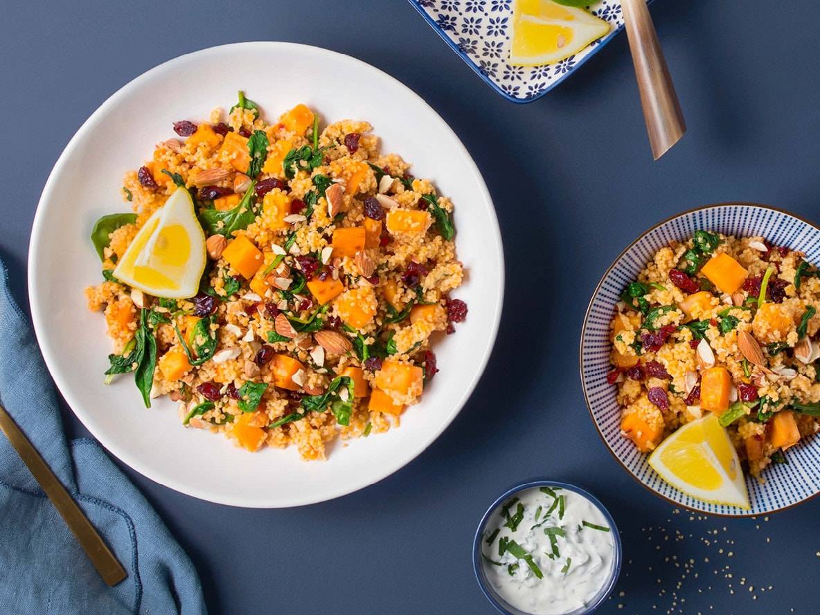 Salade de couscous avec courge, épinards, amandes et canneberges, quartiers de citron et sauce.
