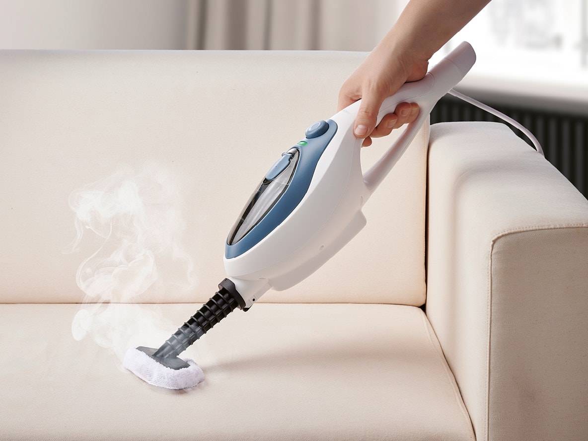 Pulitore a vapore portatile che pulisce un divano beige