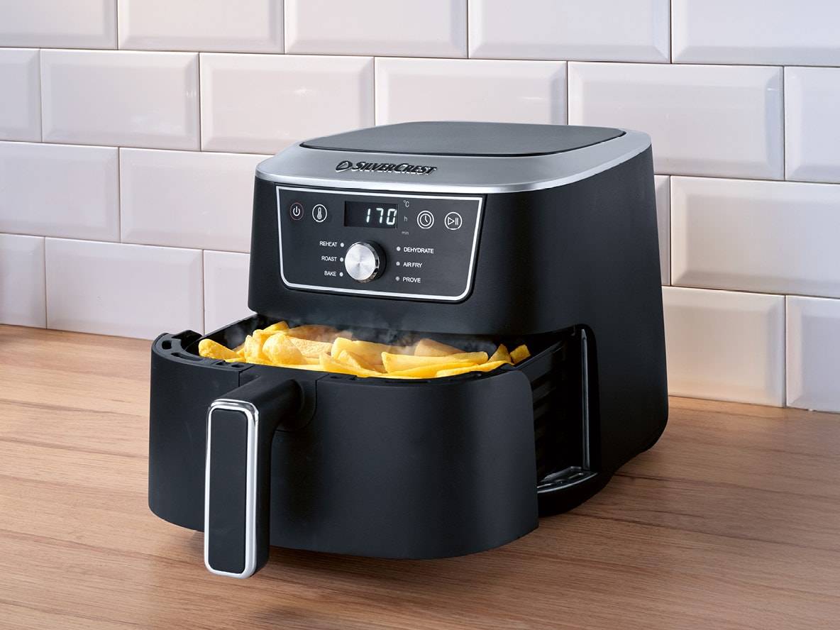 Schwarze Heißluftfritteuse mit goldenen Pommes Frites, Anzeige 170°C, auf einer Holztheke.