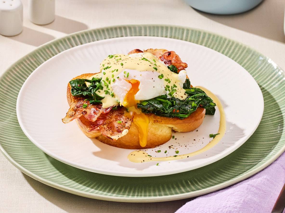 Œufs Bénédicte avec bacon, épinards et sauce hollandaise sur du pain grillé.