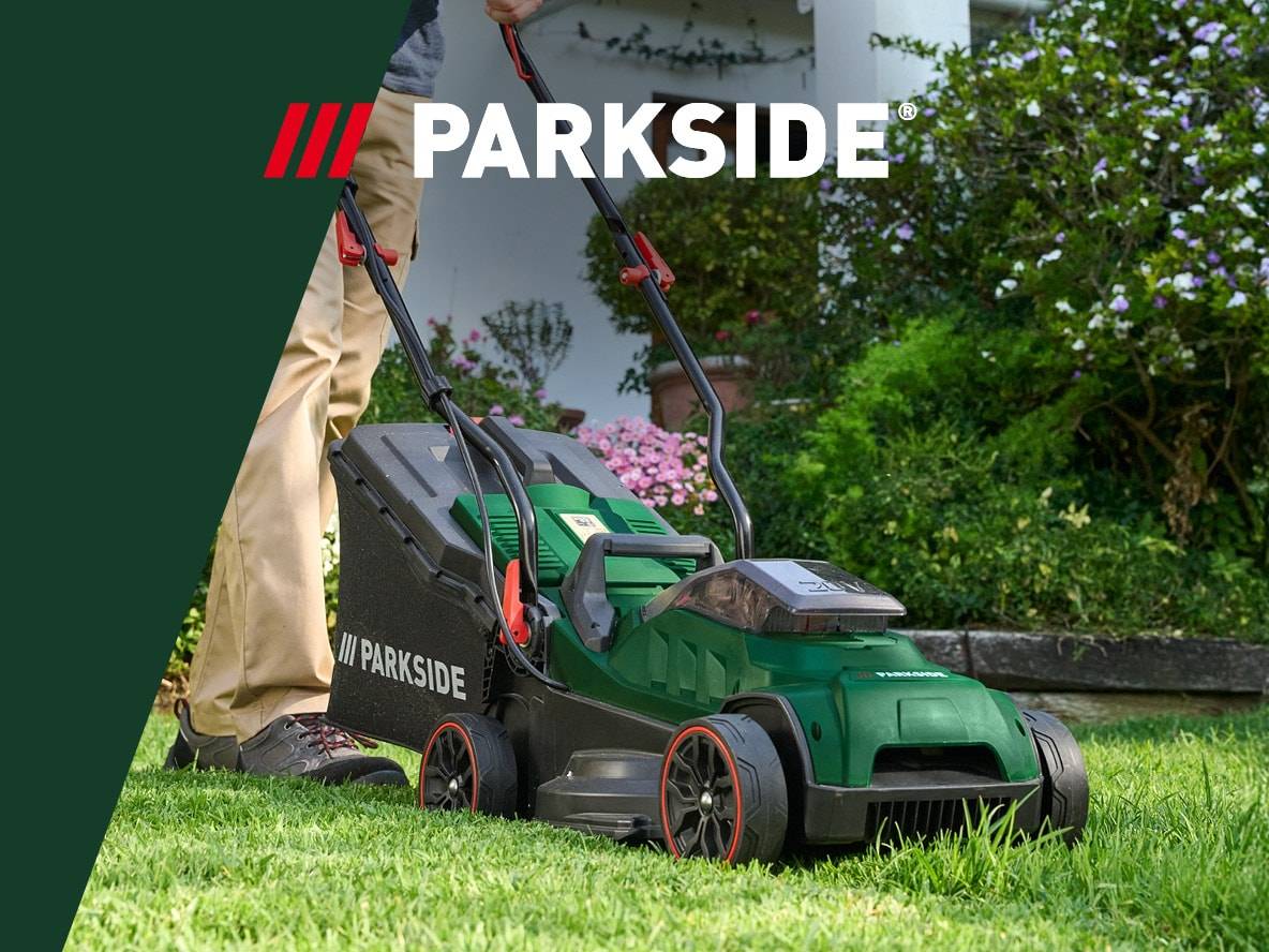 Ein Mann mäht Rasen mit einem grünen Rasenmäher auf einer grünen Wiese.