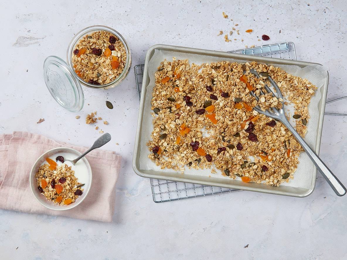 Hausgemachtes Granola mit Trockenfrüchten und Samen, serviert mit Joghurt und in einem Glas.