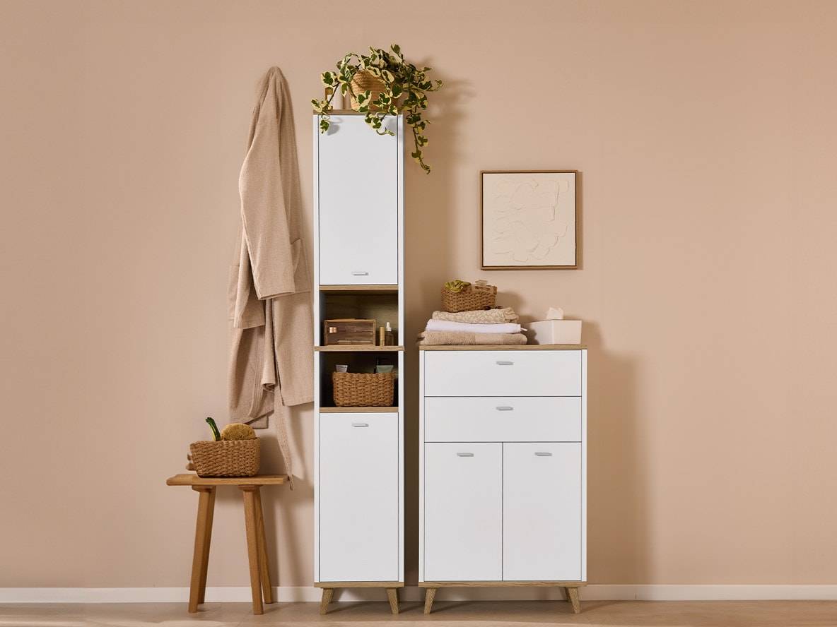 Weiße und holzfarbene Badezimmermöbel mit Hochschrank, Kommode und Holzhocker.