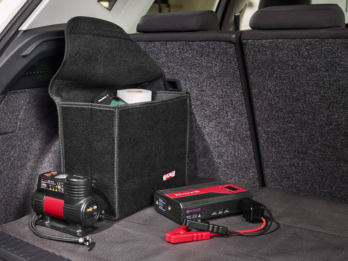 Luftkompressor und Starthilfe im Kofferraum eines Autos mit einem Organizer.