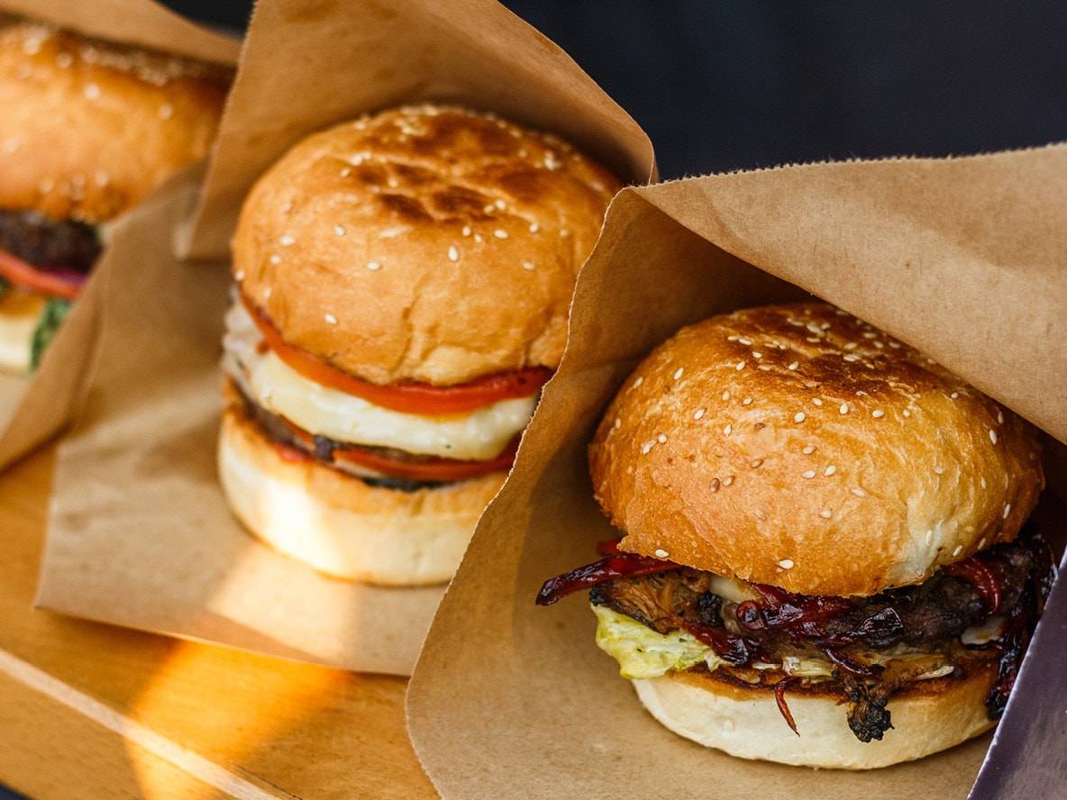 Tre hamburger in sacchetti di carta, con ripieni assortiti.