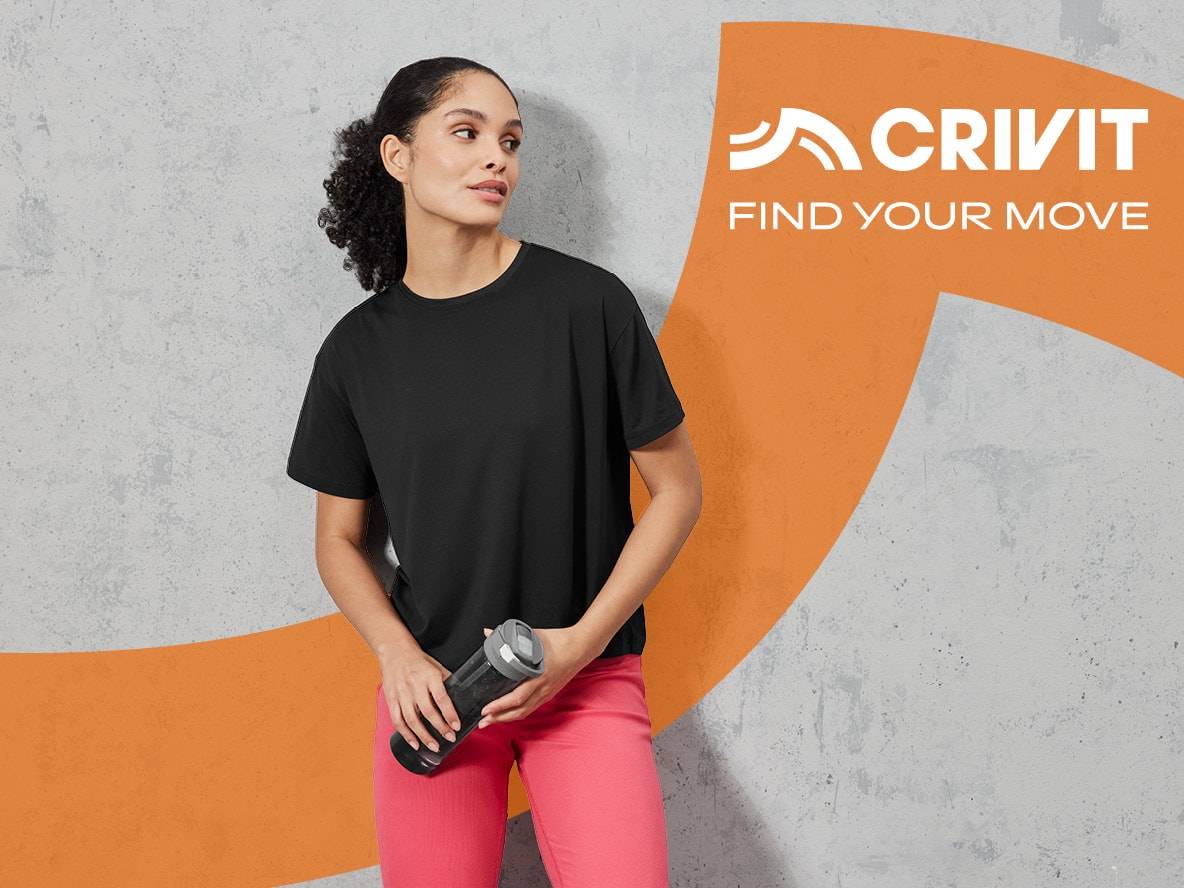 Eine Frau trägt ein schwarzes Crivit T-Shirt und rosa Leggings und hält eine Wasserflasche.