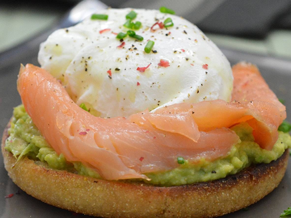 Pochiertes Ei mit Lachs und Avocado auf einem Muffin.