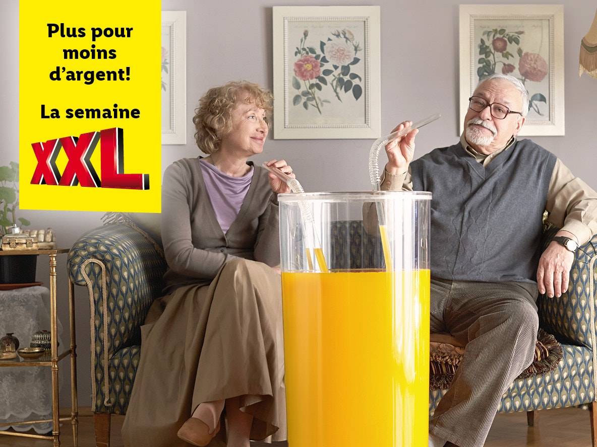 Annonce XXL pour une semaine de promotions : un couple d'âge mûr profite d'un grand verre de jus d'orange.