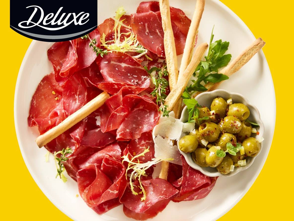 Deluxe Aufschnittplatte mit Bresaola, Grissini und marinierten Oliven.