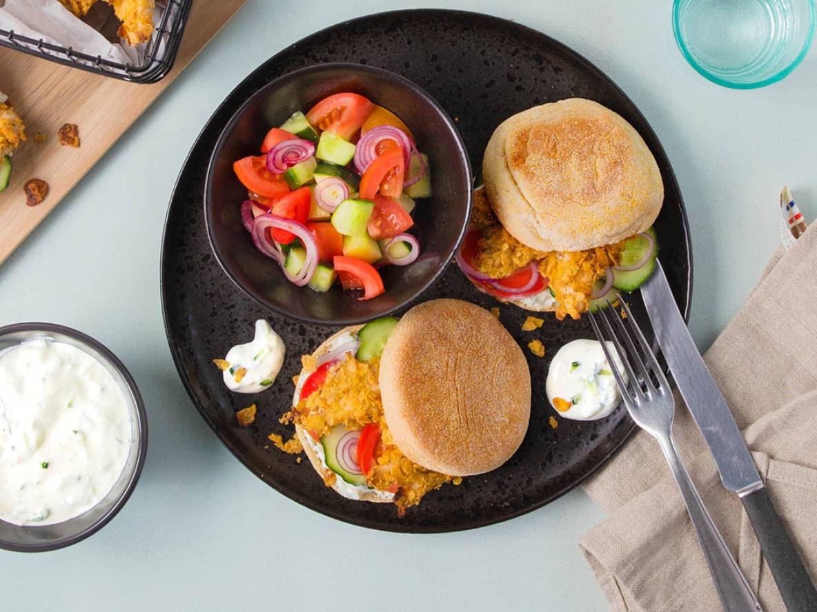 Due hamburger di pollo croccante serviti con insalata e salsa allo yogurt.