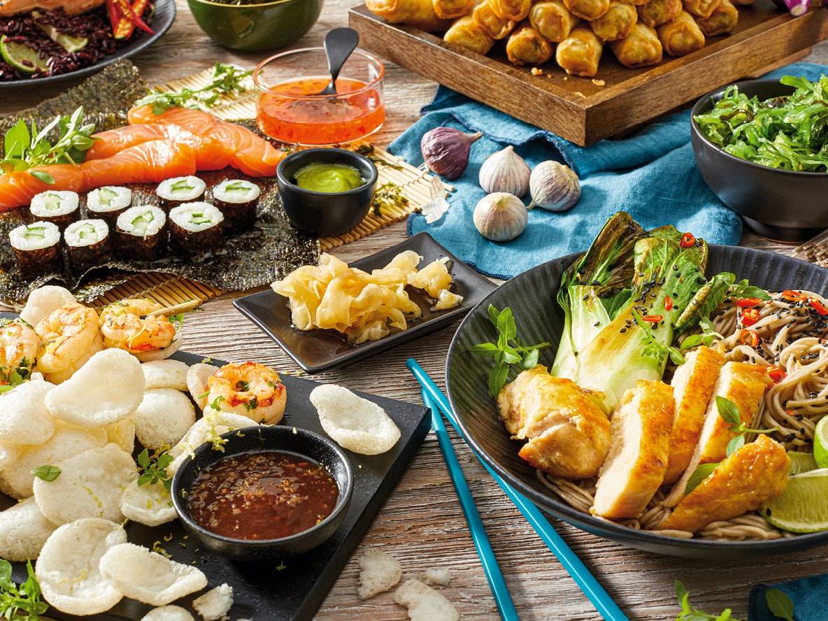 Ein asiatisches Buffet mit Sushi, Frühlingsrollen, Nudeln und Sashimi.