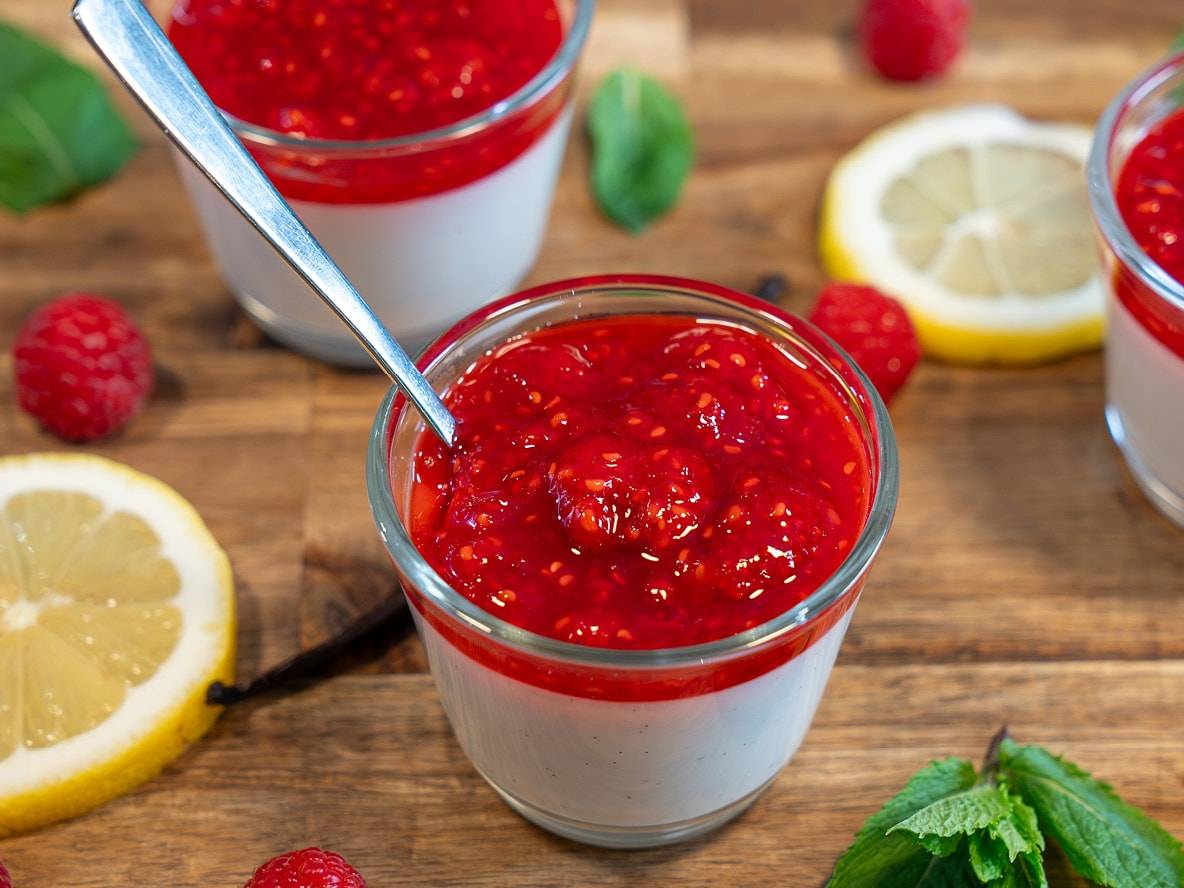 Deliziosi bicchieri di panna cotta al vaniglia, sormontati da una salsa di lamponi.