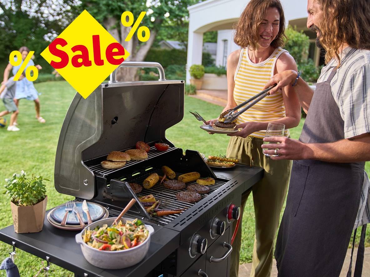 Ein Paar grillt im Garten, mit einem großen gelben „Sale“-Schild als Überlagerung.