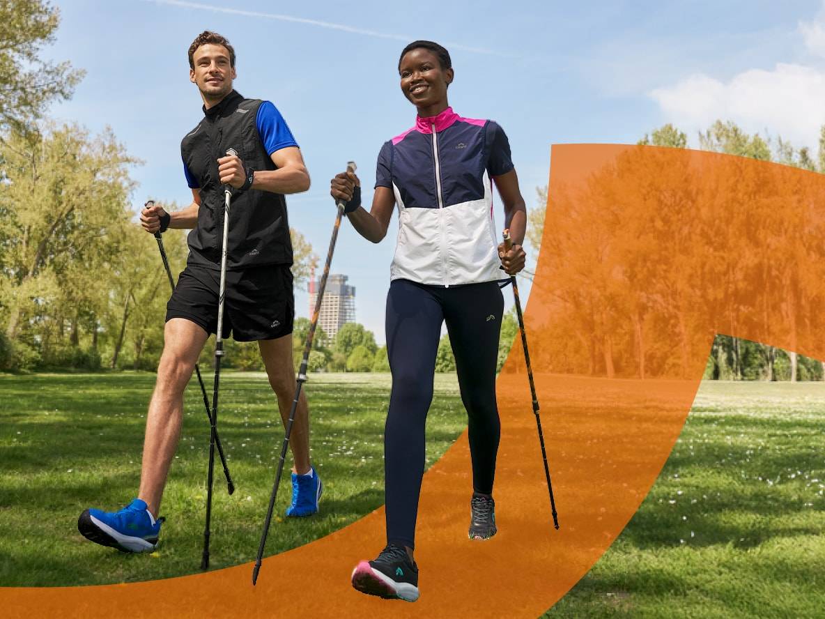 Zwei Personen beim Nordic Walking in Sportkleidung mit Stöcken in einem Park.