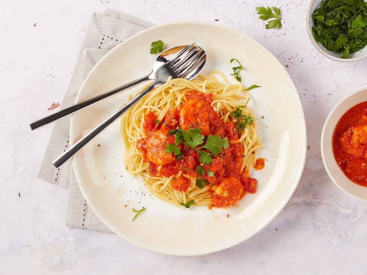 Spaghetti mit Garnelen in Tomatensauce, garniert mit frischer Petersilie.