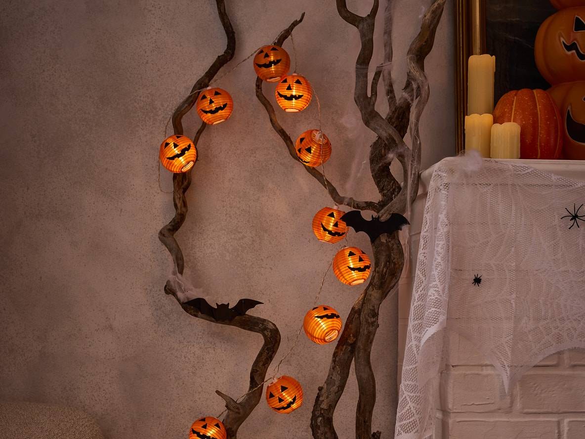 Halloween-Kürbis-Lichterkette an dekorativen Ästen mit Fledermäusen.