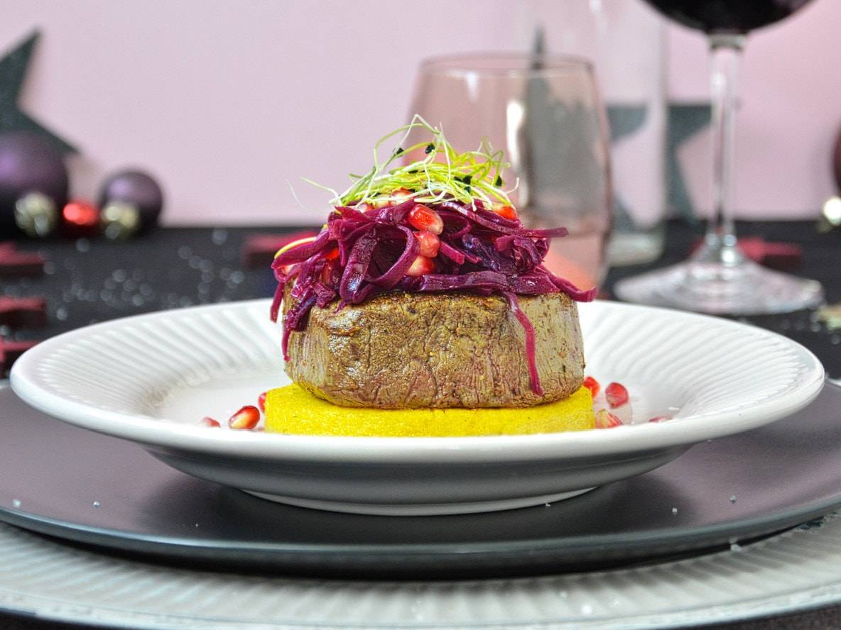 Rinderfilet auf Polenta mit Rotkohl und Granatapfel, festlich dekoriert.