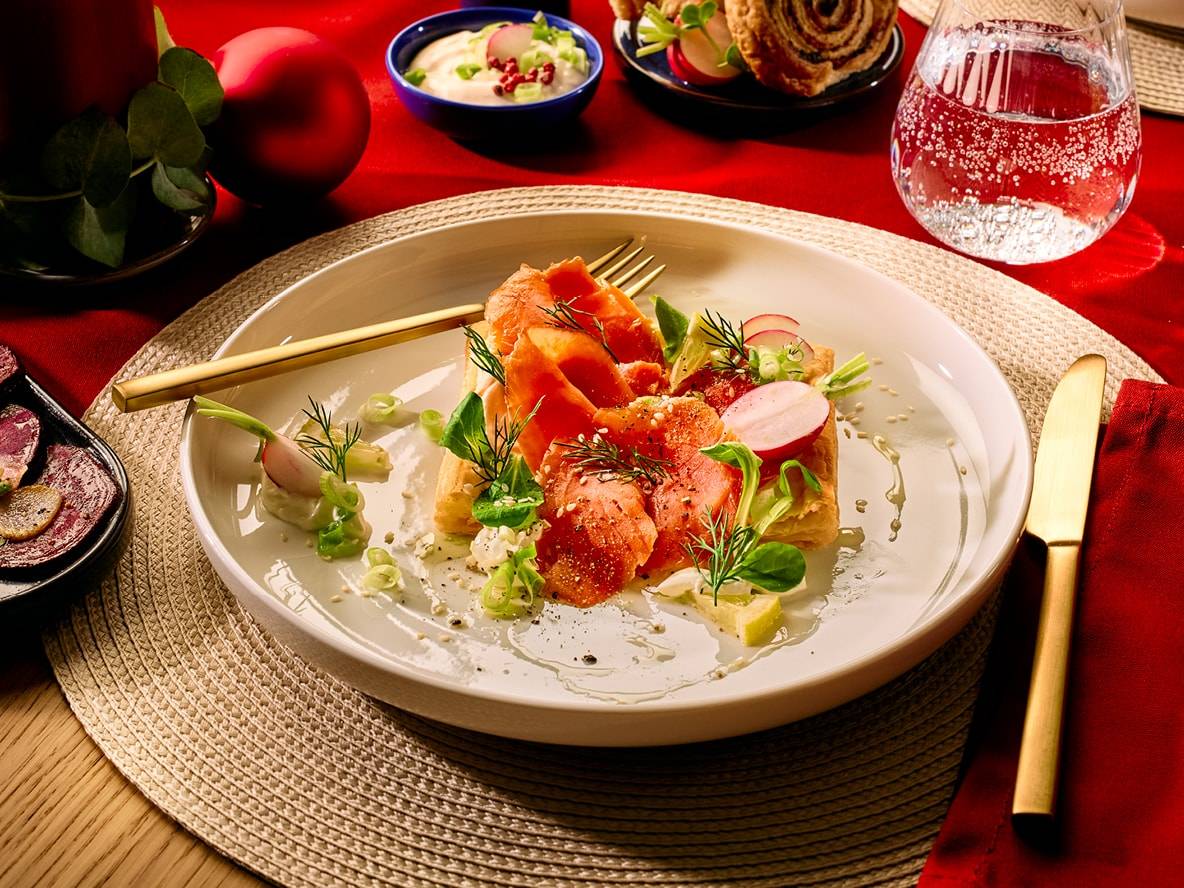 Geräucherter Lachs auf Blätterteig mit Radieschen und Dill, auf einem festlichen Tisch.