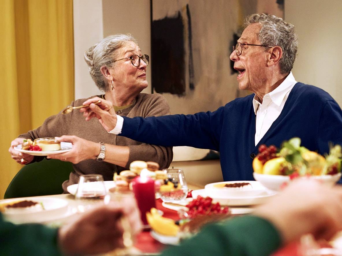 Älteres Paar teilt Dessert an festlich gedecktem Tisch.