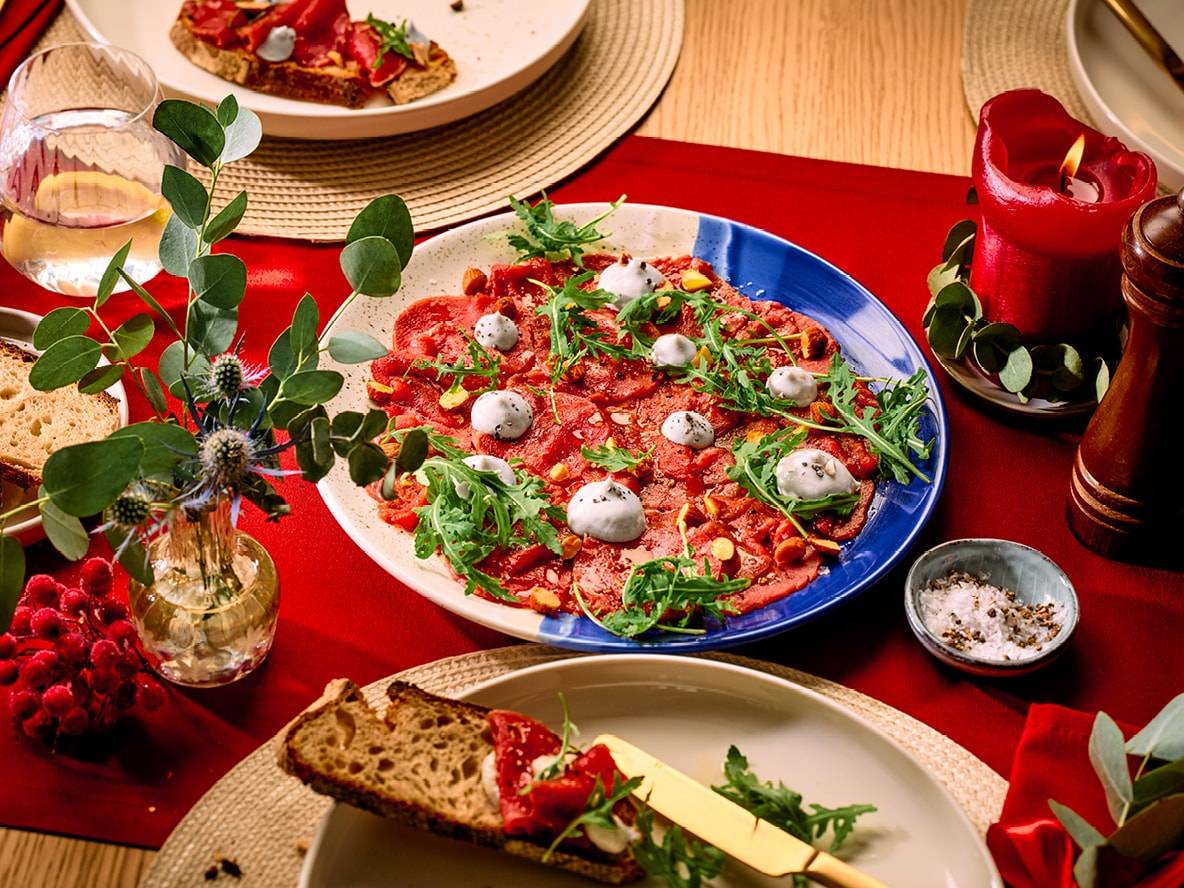 Carpaccio de bœuf avec roquette et mozzarella, bruschetta, bougie rouge et décorations de Noël.