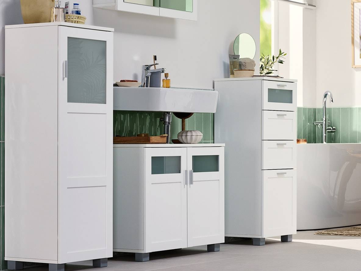 Weiße Badezimmermöbel mit Waschbecken und Badewanne, mintgrüne Fliesen.