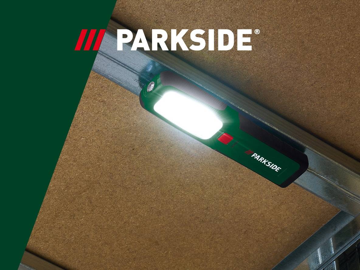 Parkside Arbeitsleuchte an Metallkonstruktion befestigt, beleuchtet eine Holzdecke.