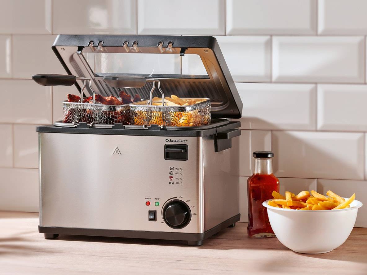 SilverCrest Fritteuse mit Pommes und Hähnchenflügeln, Soße und Pommes-Schale.