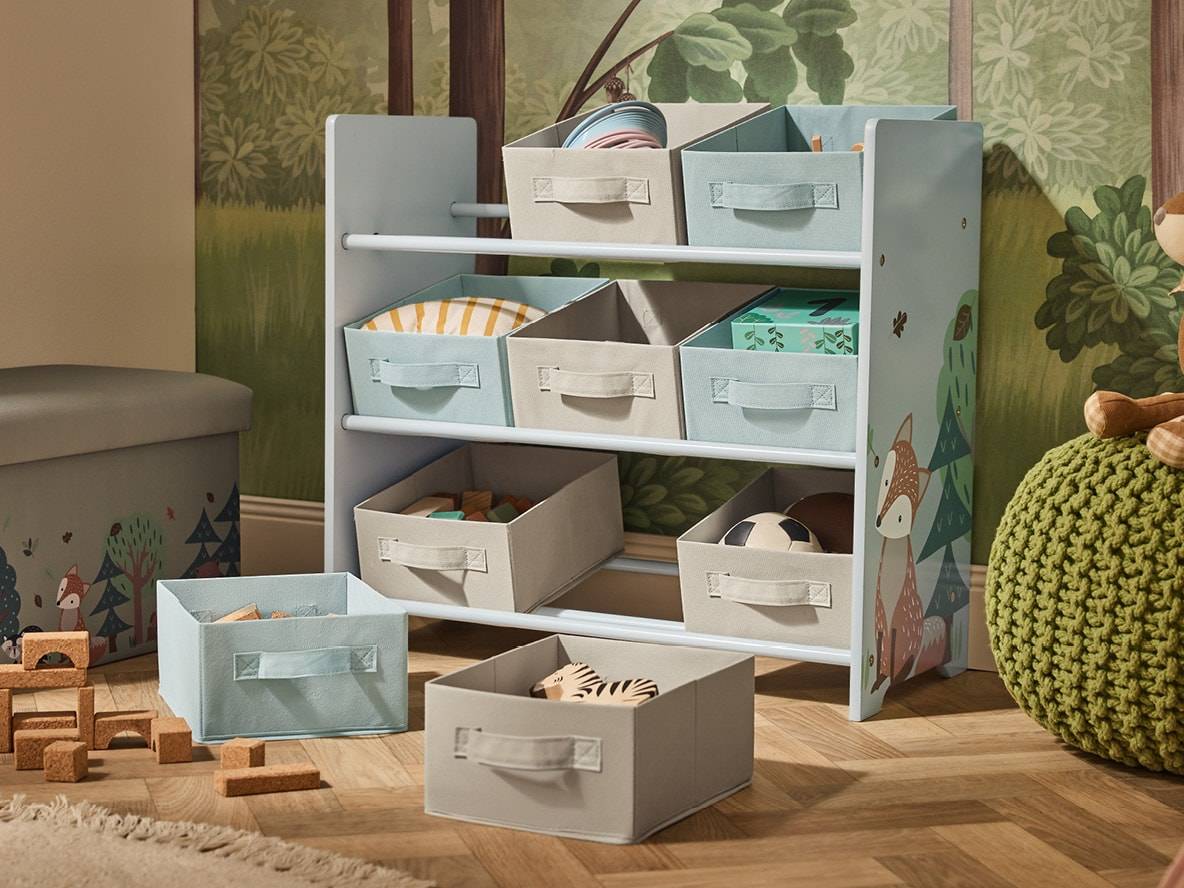 Kinderregal mit Stoffkörben und Waldmotiv, gefüllt mit Spielzeug.