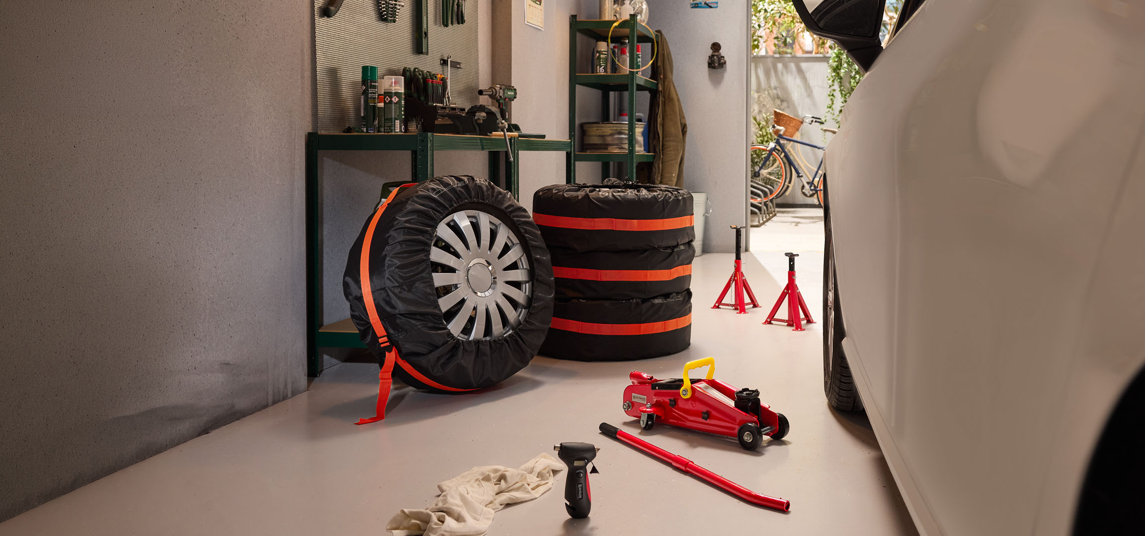 Pneumatici invernali conservati in garage con un cric e cavalletti.