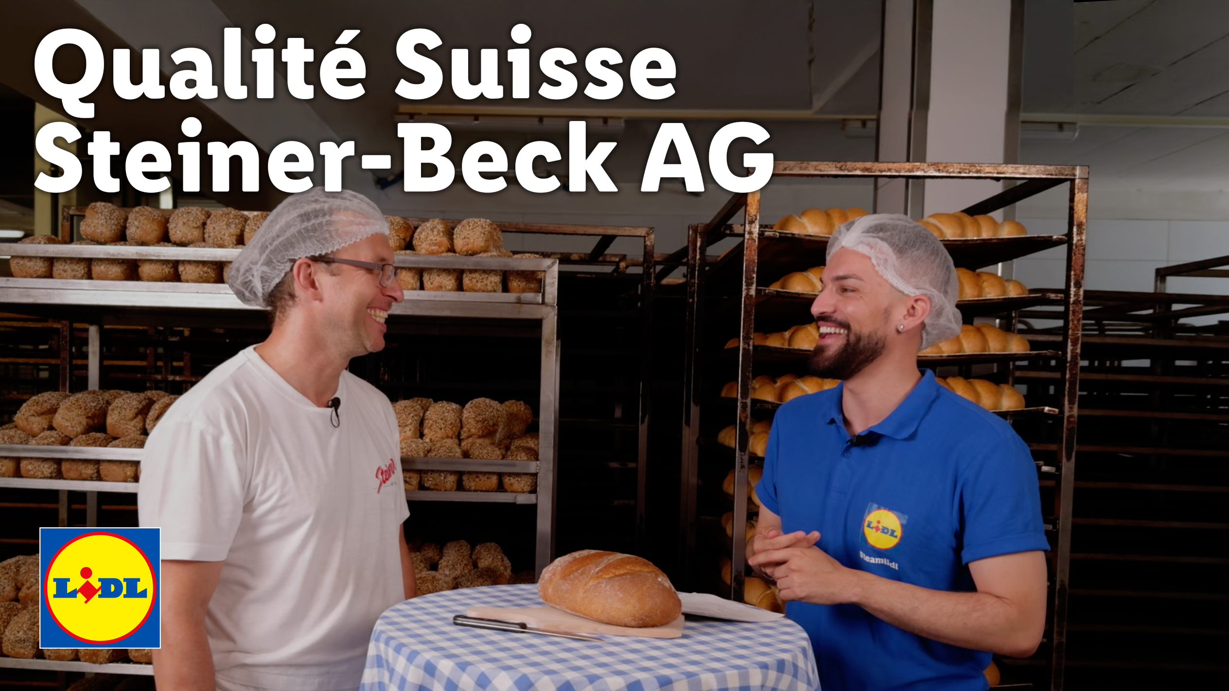 Zwei Männer in einer Bäckerei mit Brot und Brötchen, einer trägt ein Lidl-T-Shirt.