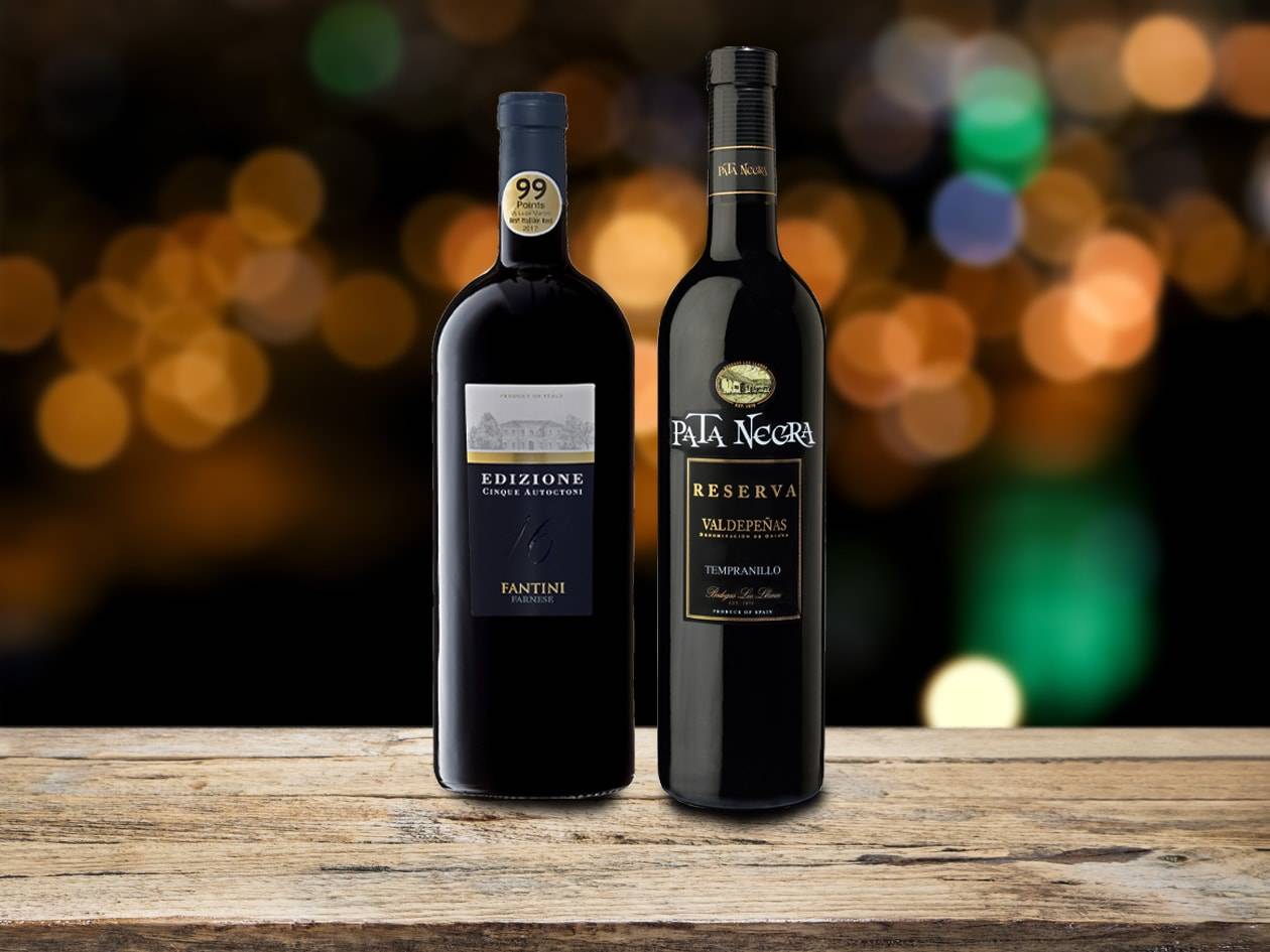 Due bottiglie di vino rosso su un tavolo di legno con sfondo sfocato.