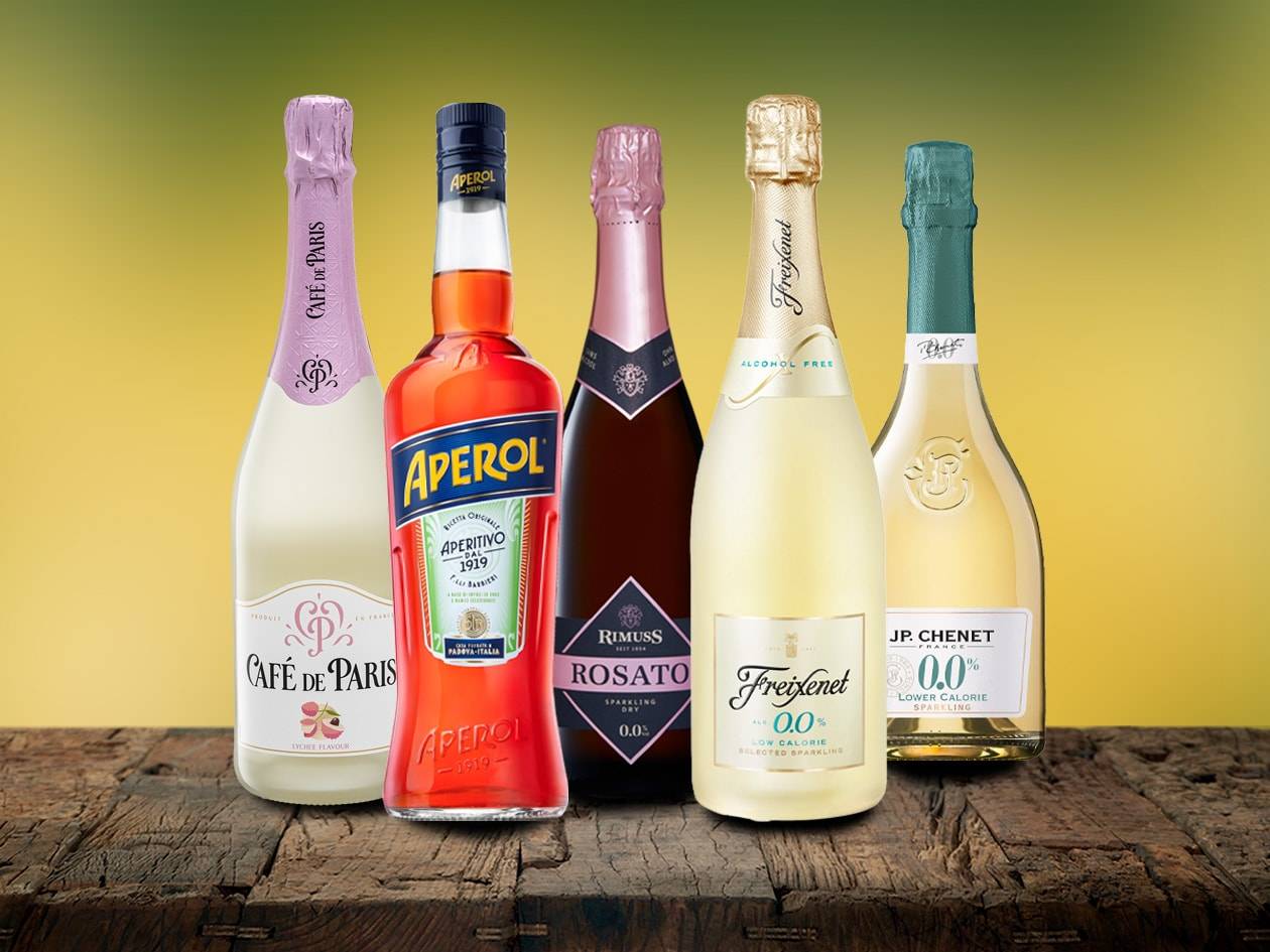 Aperitif- und Sektflaschen, darunter alkoholfreie und kalorienarme Optionen, auf einer Holzoberfläche.