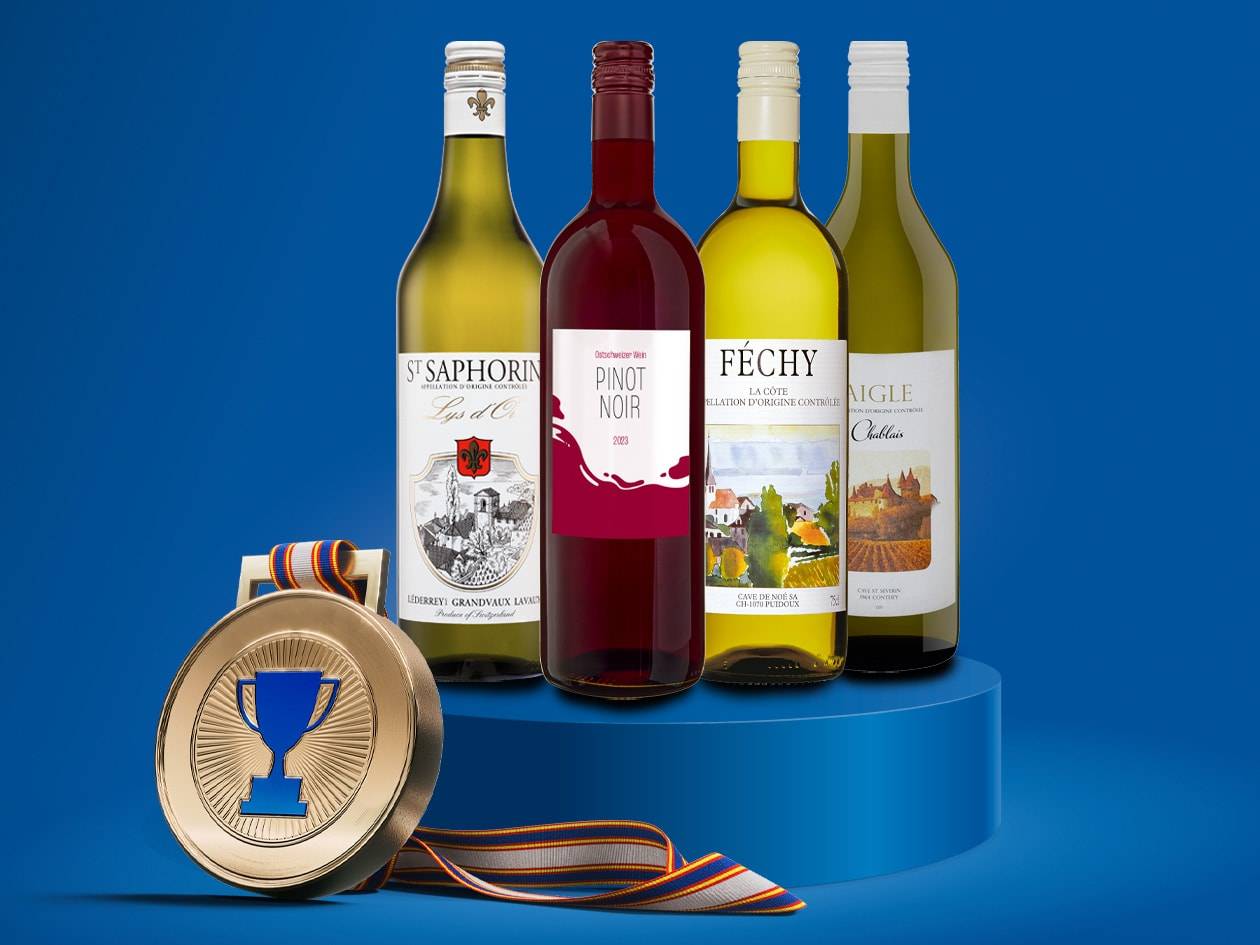 Quattro bottiglie di vino, due bianche e due rosse, con una medaglia d'oro su un piedistallo blu.