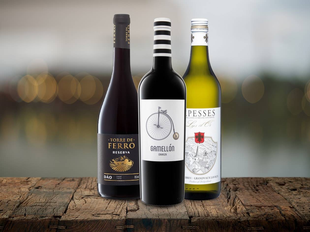 Drei Weinflaschen, darunter Torre de Ferro und Gamellón, auf einem Holztisch.