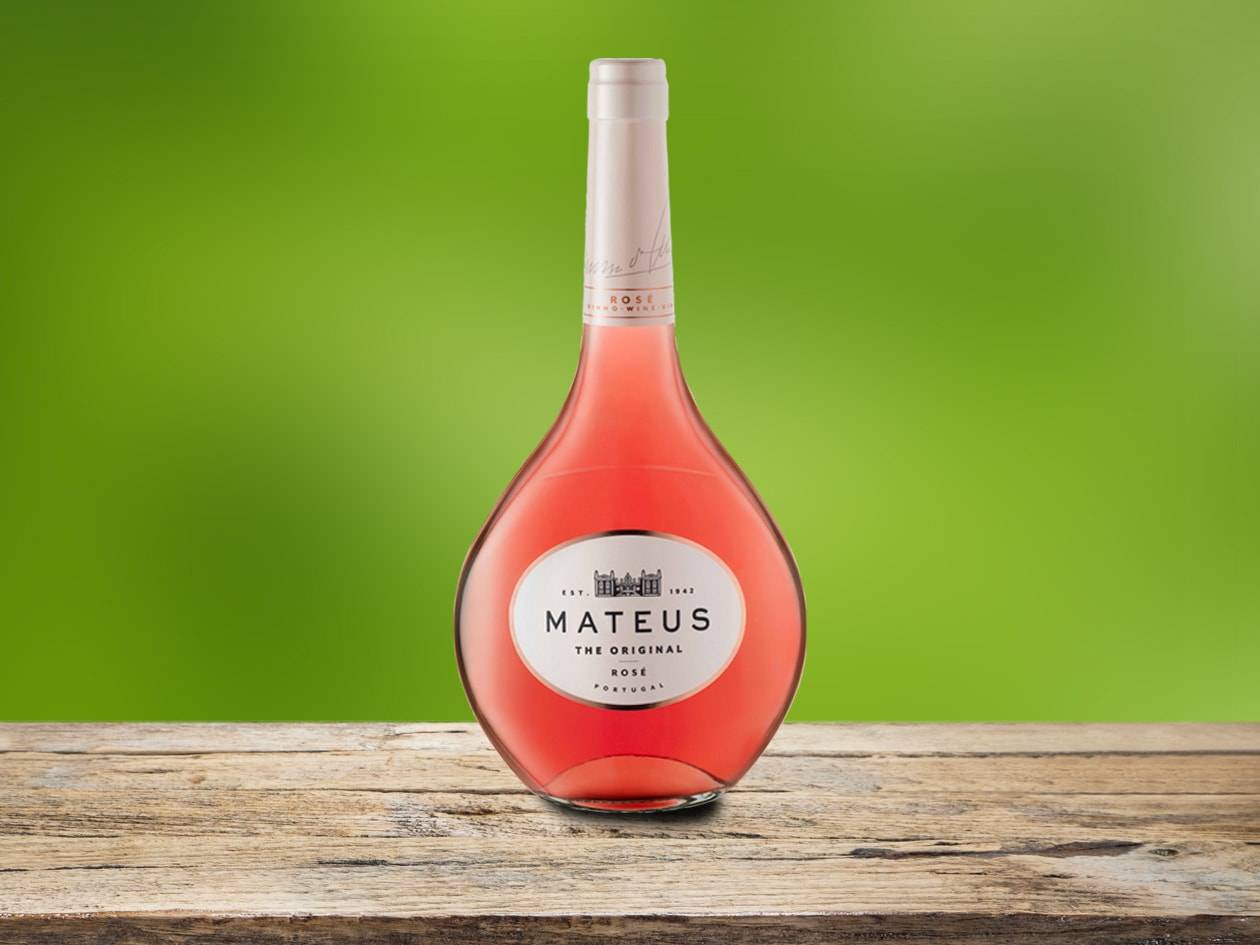Flasche Roséwein auf einem Holztisch vor grünem Hintergrund.