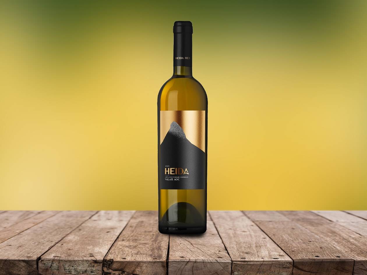 Eine Flasche Weißwein mit schwarzem und goldenem Etikett auf einem Holztisch.