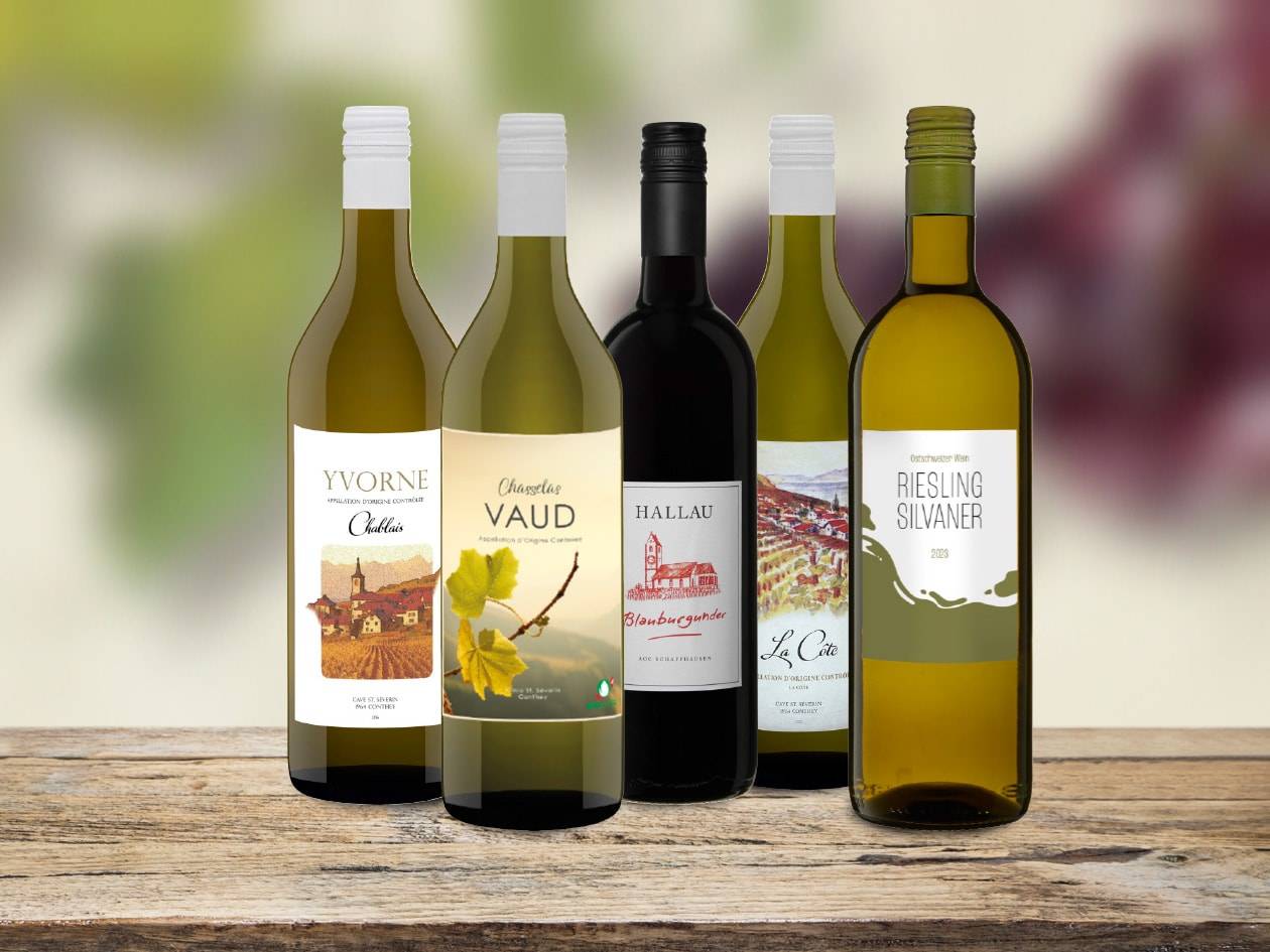 Fünf Weinflaschen, darunter Riesling Silvaner, Chasselas Vaud und Blauburgunder, auf einem Holztisch.